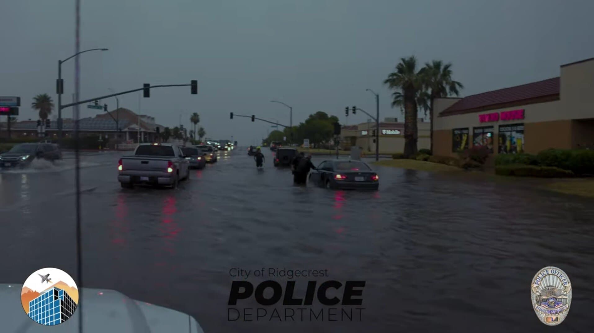 Flooded Ridgecrest street at dusk with residents wading through the water