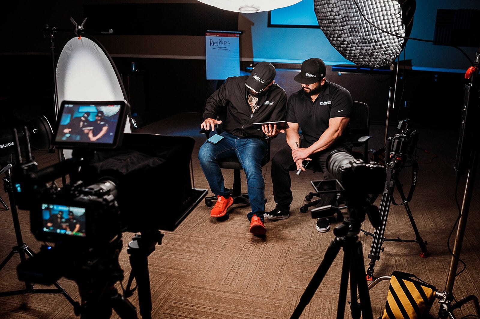 Two Raw Media Pros filmmakers reviewing footage on a tablet in the studio
